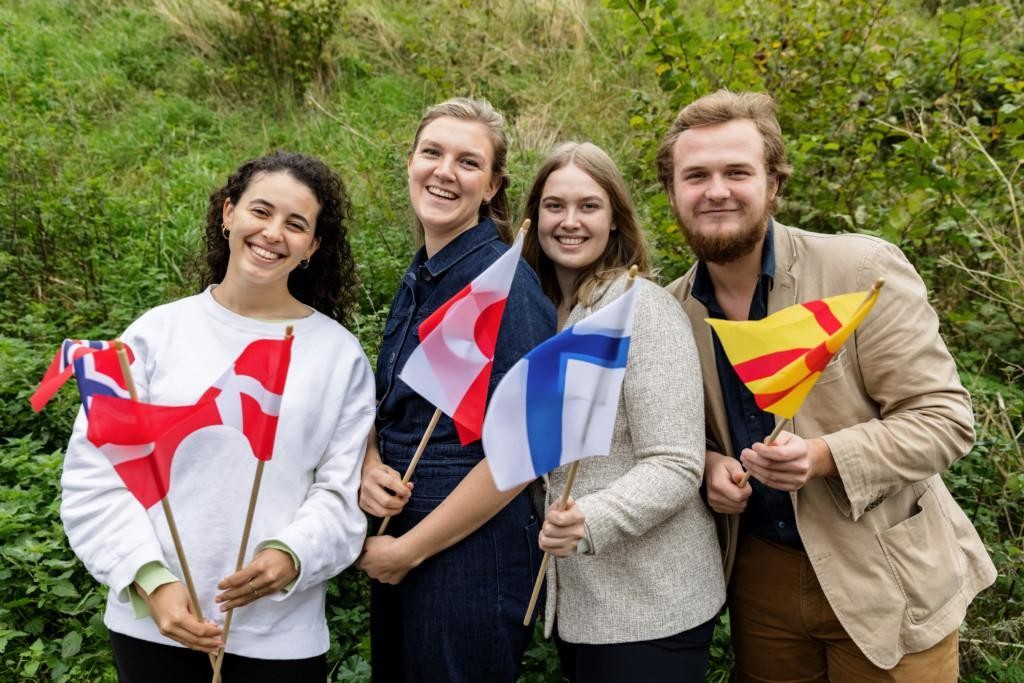 Neljä nuorta ulkoilmassa pohjoismaisten lippujen kanssa
